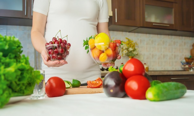 Una mujer embarazada come vegetales y frutas.