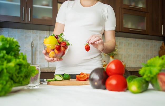 Una mujer embarazada come vegetales y frutas.