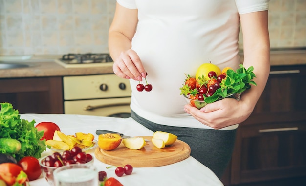 Una mujer embarazada come vegetales y frutas.