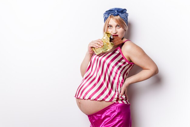 Mujer embarazada comiendo una barra de chocolate