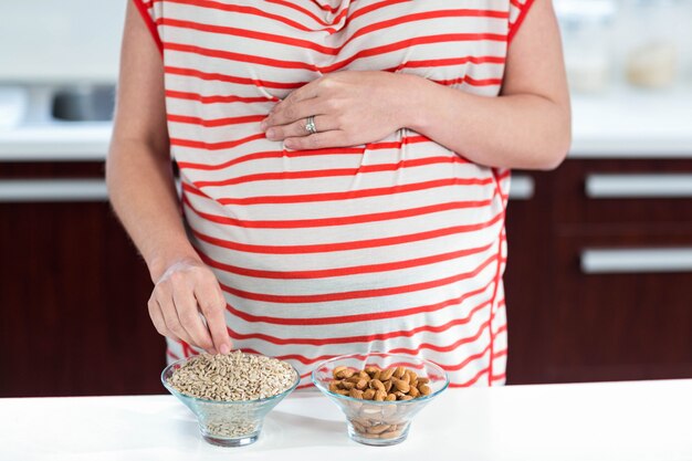 Mujer embarazada comiendo cereales en la cocina