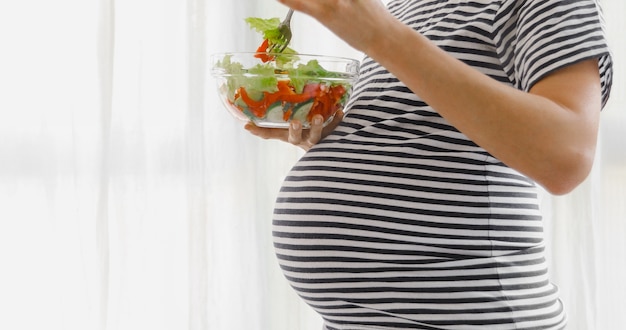 Mujer embarazada comiendo ensalada de cosecha