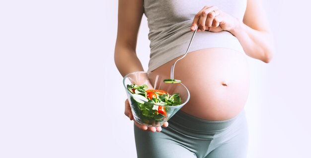 Mujer embarazada comiendo saludable closeup vientre de mujer embarazada y ensalada de verduras