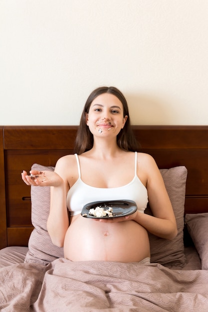 Foto mujer embarazada comiendo un trozo de tarta