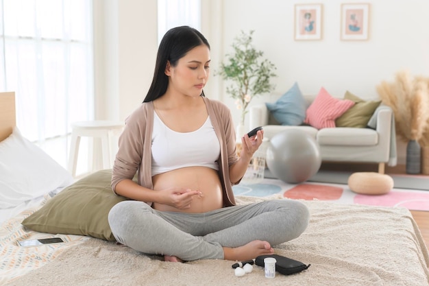 Mujer embarazada comprobando el nivel de azúcar en la sangre mediante un medidor de glucosa digital