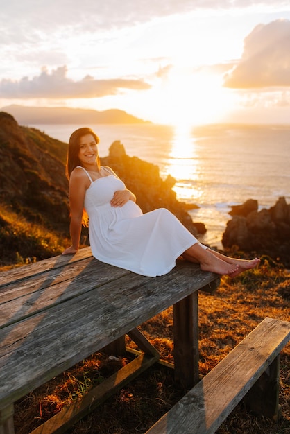 Mujer embarazada contra un paisaje oceánico al atardecer en Galicia, España