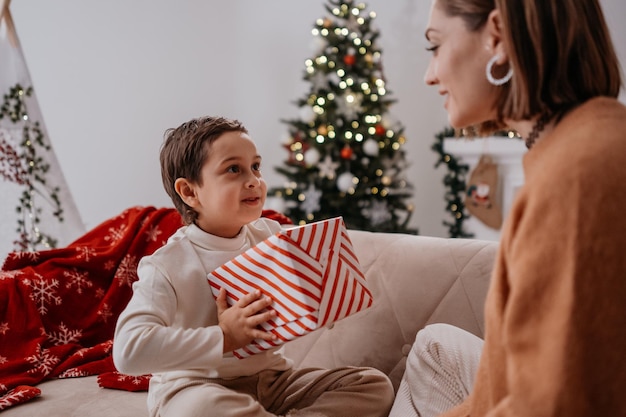 Mujer embarazada dando regalo de Navidad al niño madre soltera pasando tiempo con el hijo en casa y