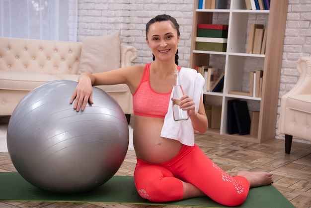 Mujer embarazada descansa después de entrenar en casa