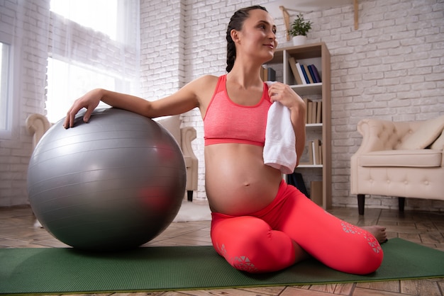 Mujer embarazada descansa después de entrenar en casa