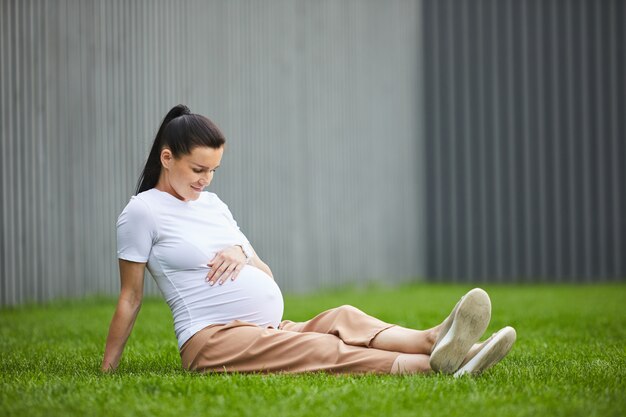 Mujer embarazada descansando sobre la hierba