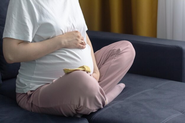 Mujer embarazada descansando sola en casa acaricia toca su gran barriga