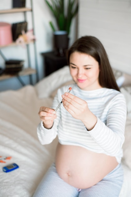 Foto mujer embarazada con diabetes por jeringa en el concepto del hogar.