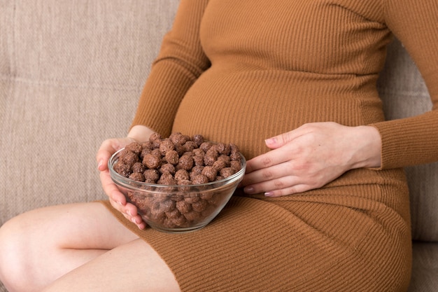 La mujer embarazada disfruta comiendo bolas de cereal de chocolate crujientes