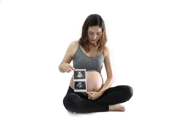 Mujer embarazada disfrutando de la futura maternidad con la primera foto de ultrasonido de su bebé