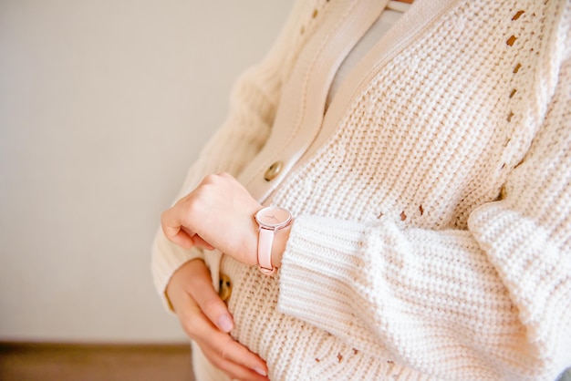 Mujer embarazada esperando bebé en casa, comprobando el tiempo en el reloj de pulsera, el tiempo de las contracciones