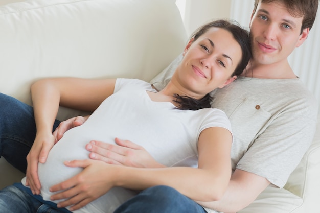 Mujer embarazada y esposo acostado en el sofá