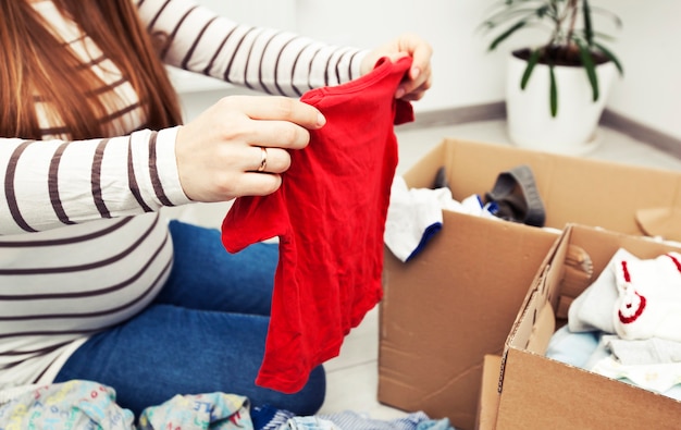 La mujer embarazada está clasificando ropa de bebé.