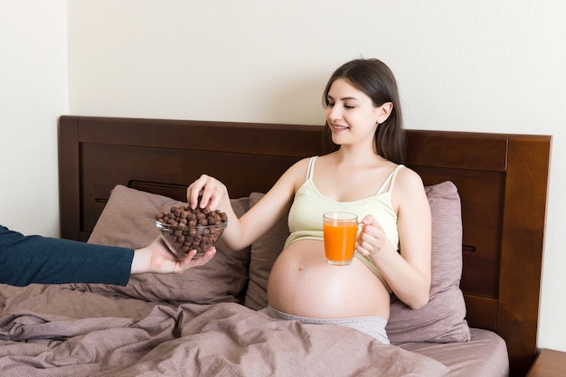 La mujer embarazada está comiendo bolas de cereal de chocolate