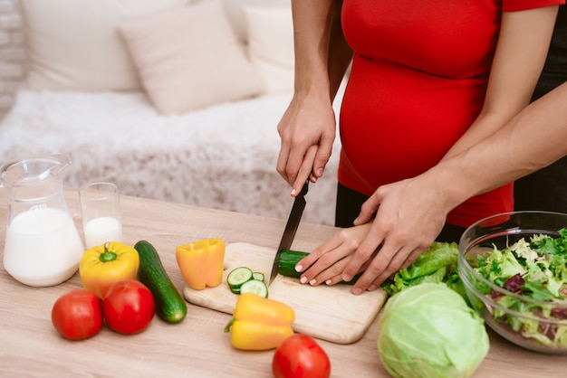 Una mujer embarazada está preparando comida con su esposo.