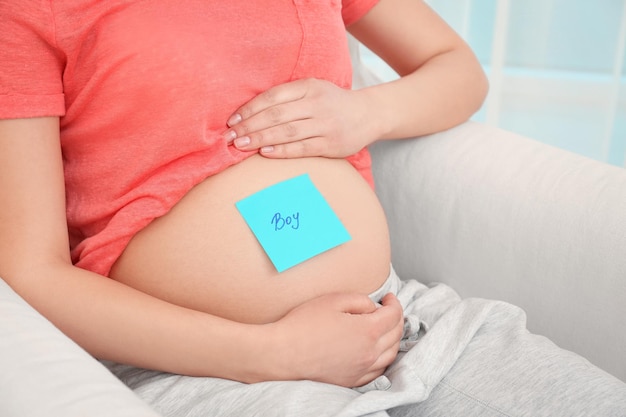 Mujer embarazada con etiqueta de papel en el primer plano de la barriga Concepto de elegir el nombre del bebé