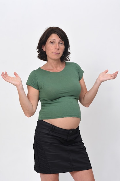 Foto mujer embarazada con una expresión de duda sobre fondo blanco.