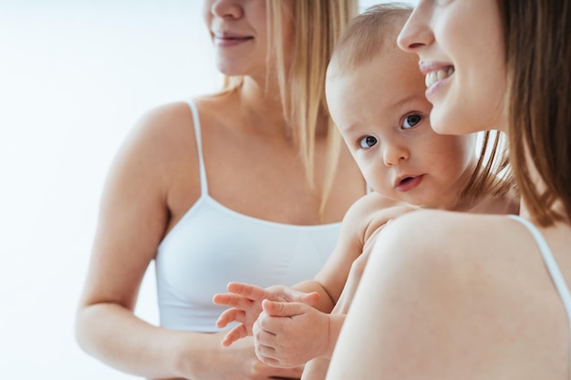 Mujer embarazada feliz con gran barriga y hermosa madre con bebé de fondo coloreado - Mujeres jóvenes usando ropa interior esperando un bebé - Embarazo, maternidad, personas y concepto de expectativa