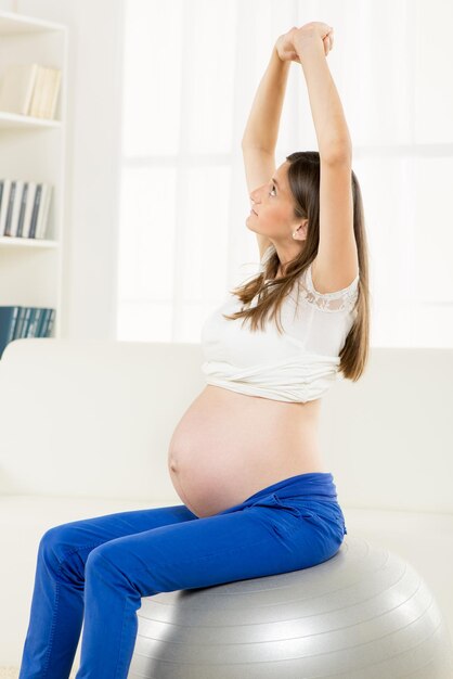 Mujer embarazada feliz haciendo ejercicio de relajación con Fitness Ball
