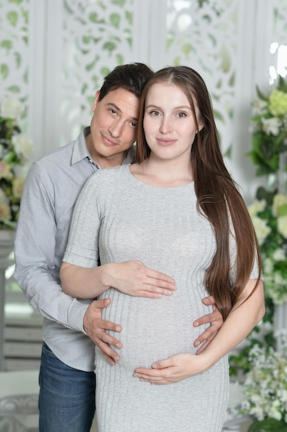 Mujer embarazada feliz con marido posando en casa