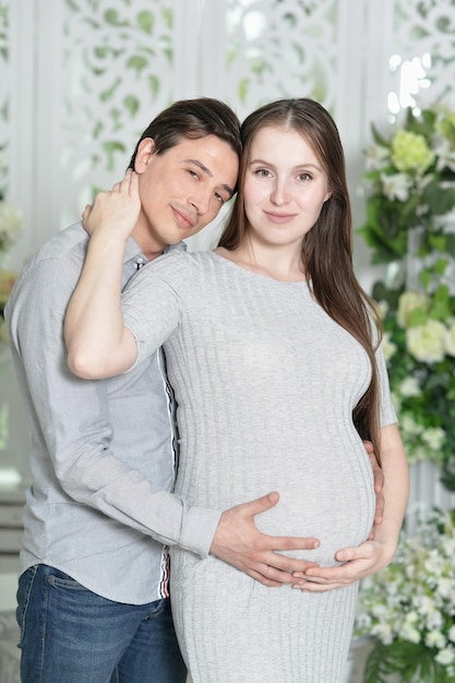 Mujer embarazada feliz con marido posando en casa