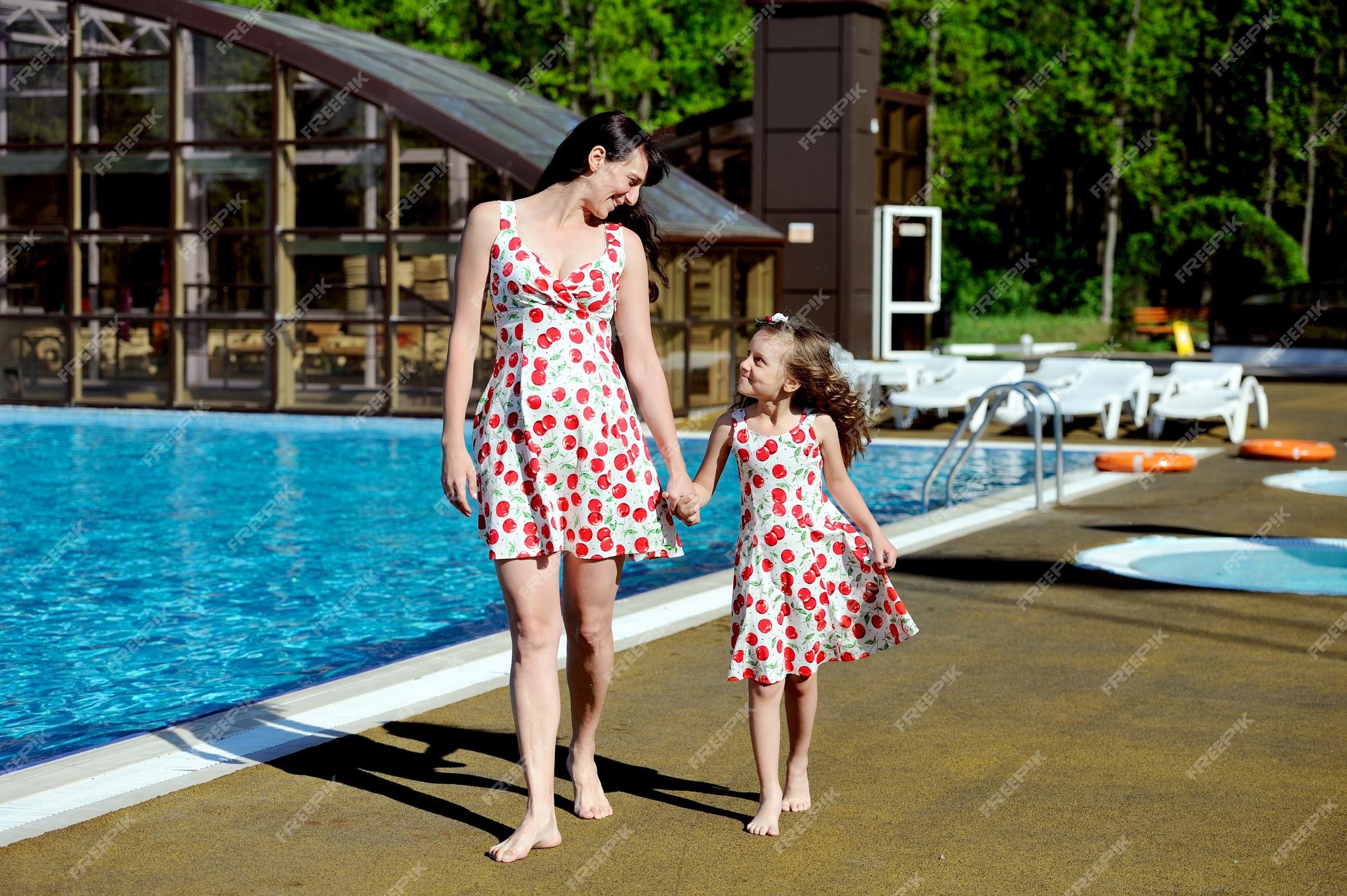 Tiempos antiguos Beneficiario lavanda Una mujer embarazada feliz y una niña con vestidos idénticos caminan por el  borde de la piscina | Foto Premium