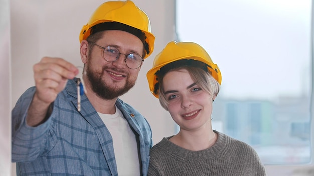 Mujer embarazada feliz con su marido que tiene llaves del nuevo apartamento