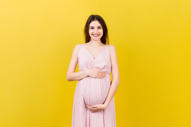 Mujer embarazada feliz tocando su abdomen en fondo de color Futura madre esperando un bebé Copiar espacio