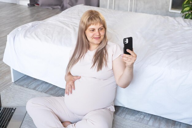 mujer embarazada con gran barriga embarazo avanzado usando teléfono haciendo selfie, haciendo videollamada