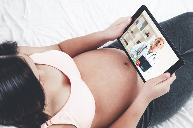Mujer embarazada hablando con el médico en línea