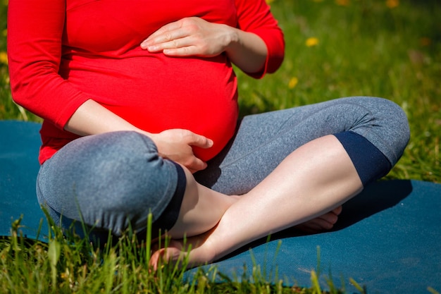 Mujer embarazada haciendo asana sukhasana al aire libre