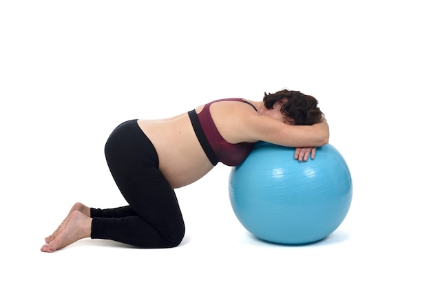 Mujer embarazada haciendo ejercicio con una pelota sobre fondo blanco.