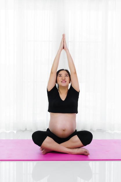 Mujer embarazada haciendo ejercicio de yoga en el salón de casa