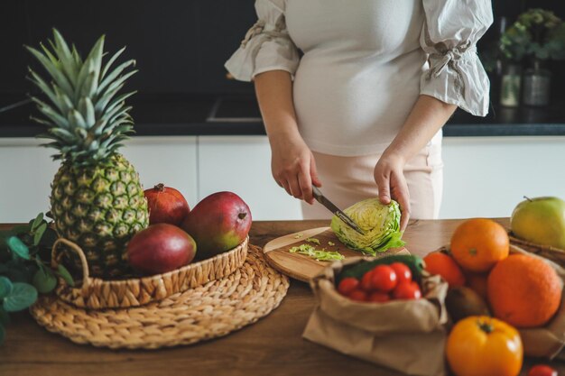 Mujer embarazada haciendo ensalada en su cocina