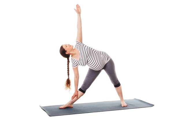 Mujer embarazada haciendo yoga asana utthita trikonasana