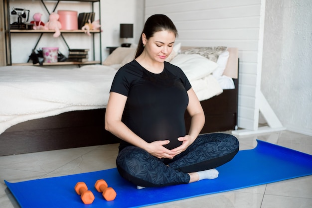 Mujer embarazada haciendo yoga en casa. Yoga y fitness durante el embarazo.