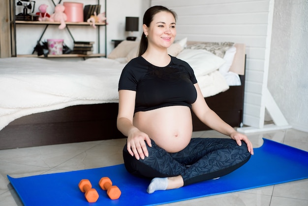 Mujer embarazada haciendo yoga en casa