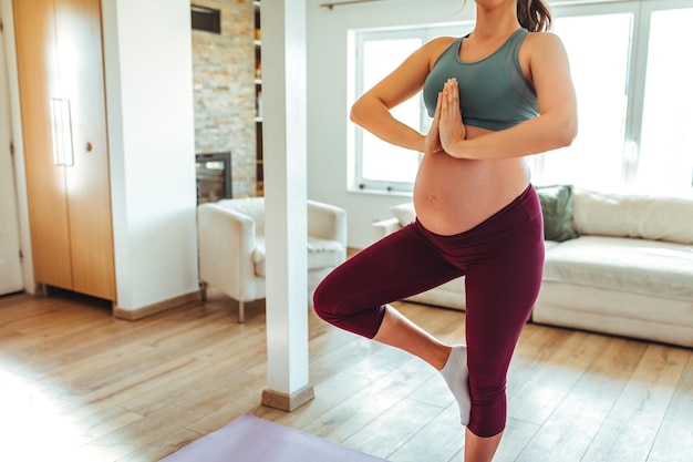 Mujer embarazada haciendo yoga en casa