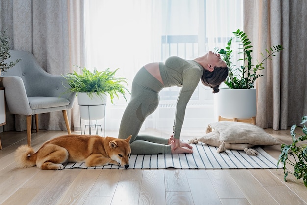 Mujer embarazada haciendo yoga prenatal en casa en la sala de estar brillante