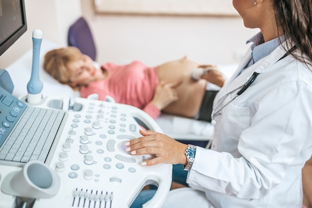 Mujer embarazada hermosa y feliz en el examen ginecológico con equipo médico de ultrasonido.