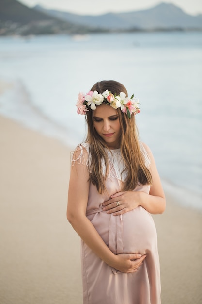 Mujer embarazada con un hermoso vestido en el océano.