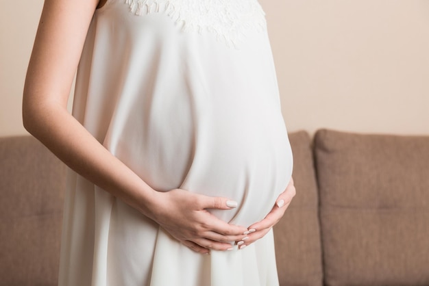 Mujer embarazada con un hermoso vestido de pie en la casa