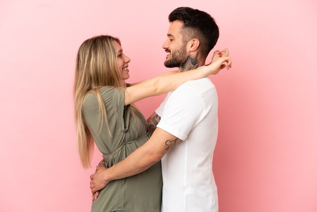 Mujer embarazada, y, hombre, encima, aislado, fondo rosa, abrazar