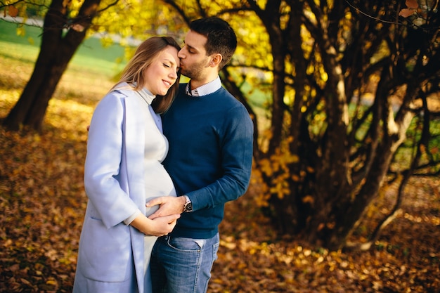 Mujer embarazada y hombre posando en el parque de otoño