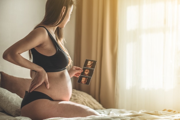 Mujer embarazada con imagen de ultrasonido. Concepto de embarazo, salud, ginecología, medicina. Joven madre esperando al bebé