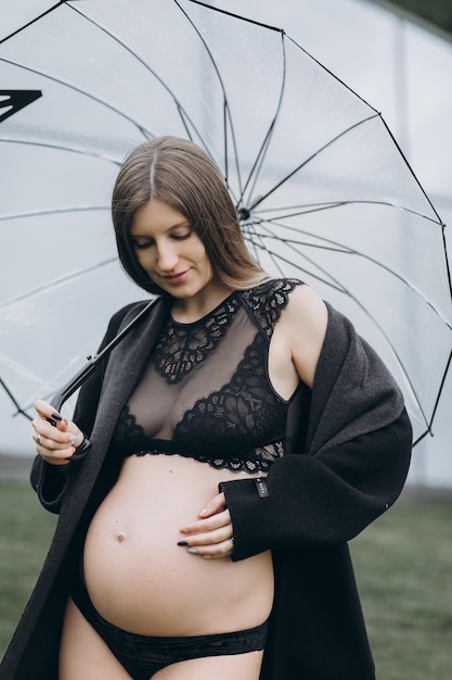 mujer embarazada en un impermeable en el parque